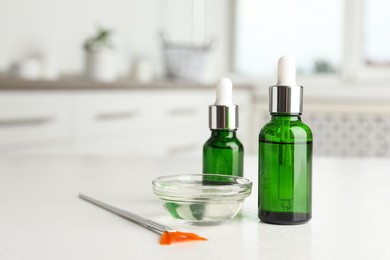 Photo of Peeling procedure. Bottles of chemical peel, bowl with liquid and brush on white table indoors. Space for text