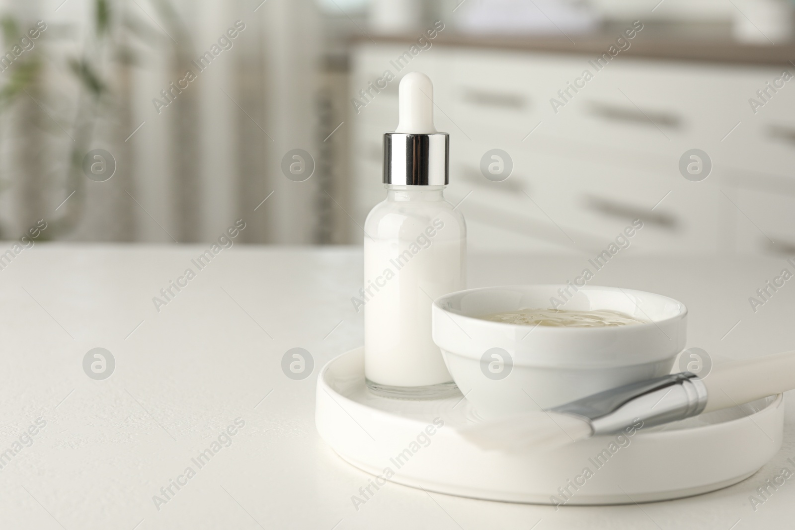 Photo of Peeling procedure. Bottle of chemical peel, bowl with liquid and brush on white table indoors. Space for text