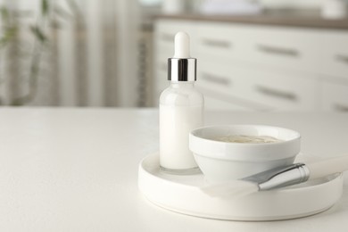 Photo of Peeling procedure. Bottle of chemical peel, bowl with liquid and brush on white table indoors. Space for text