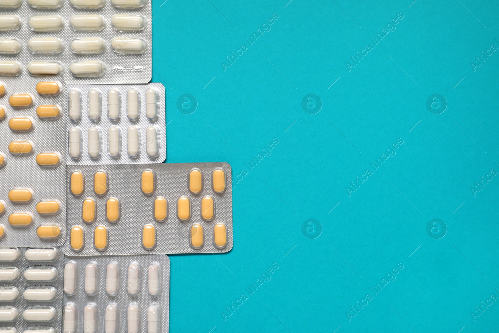 Photo of Antibiotic pills in blisters on light blue background, top view. Space for text