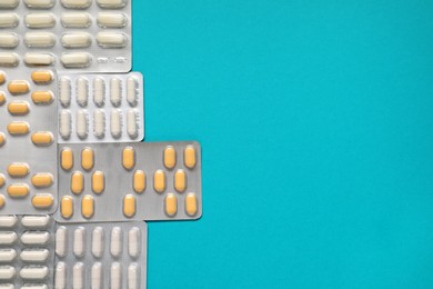 Photo of Antibiotic pills in blisters on light blue background, top view. Space for text