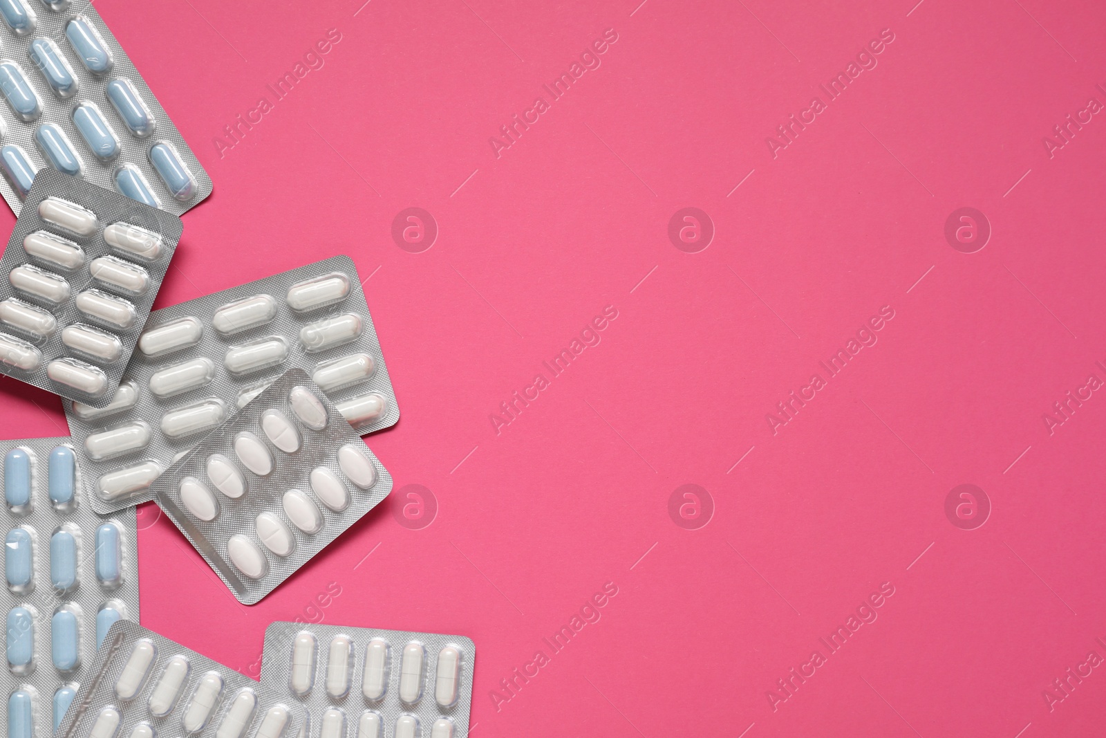 Photo of Antibiotic pills in blisters on pink background, flat lay. Space for text