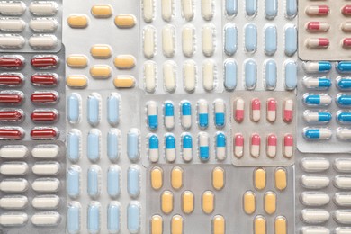 Photo of Antibiotic pills in blisters as background, top view