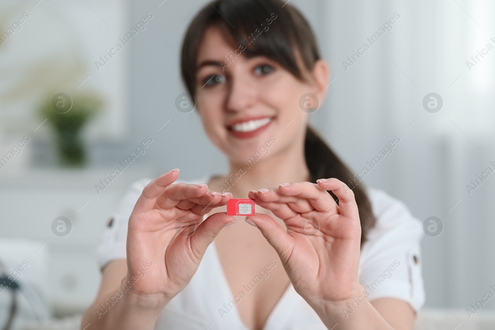 Photo of Woman holding SIM card at home, selective focus