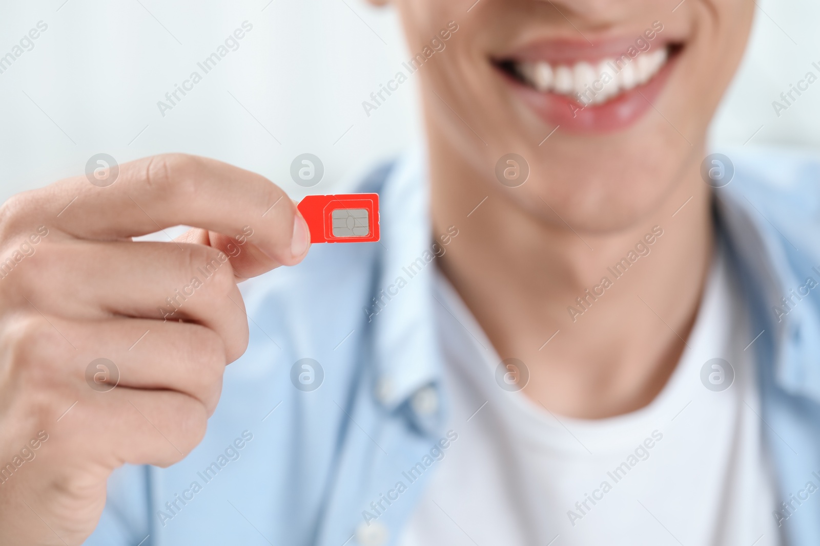 Photo of Man holding SIM card indoors, closeup view