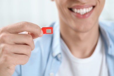 Photo of Man holding SIM card indoors, closeup view