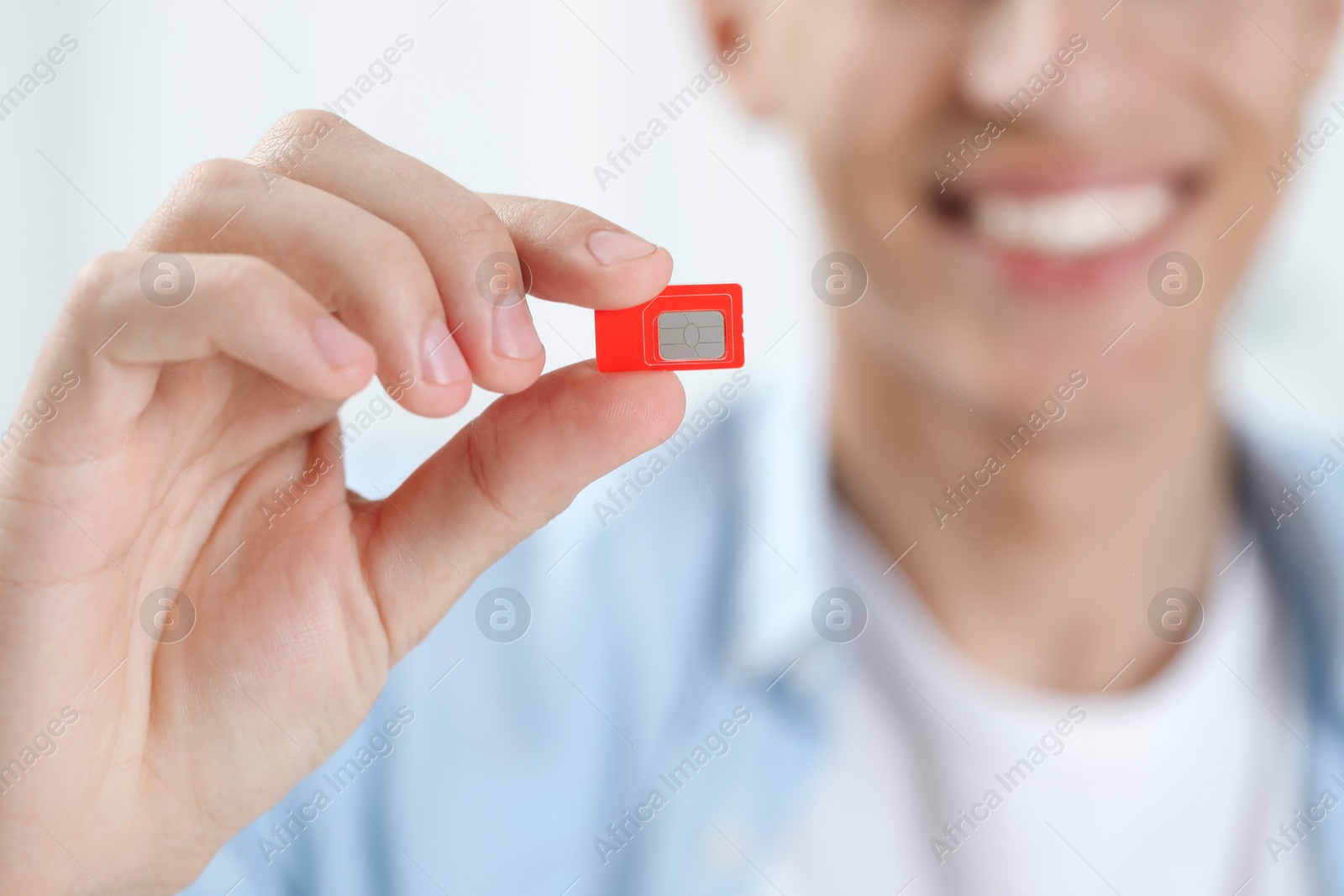 Photo of Man holding SIM card indoors, closeup view