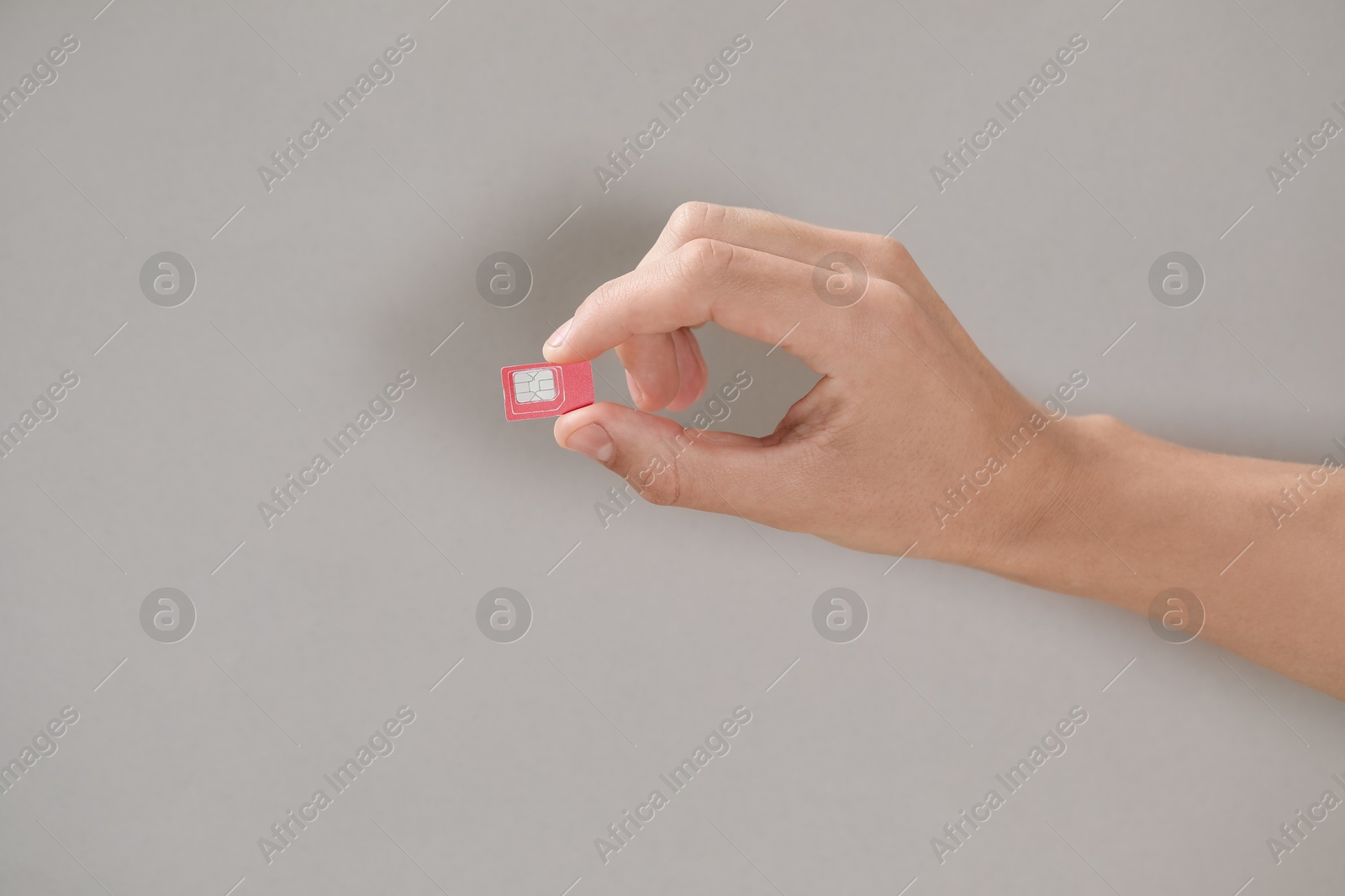 Photo of Man holding SIM card on grey background, closeup