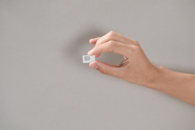 Man holding SIM card on grey background, closeup