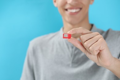 Photo of Man with SIM card on light blue background, closeup