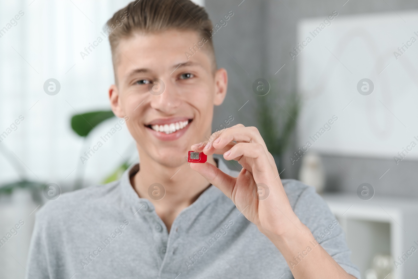 Photo of Happy man with SIM card at home