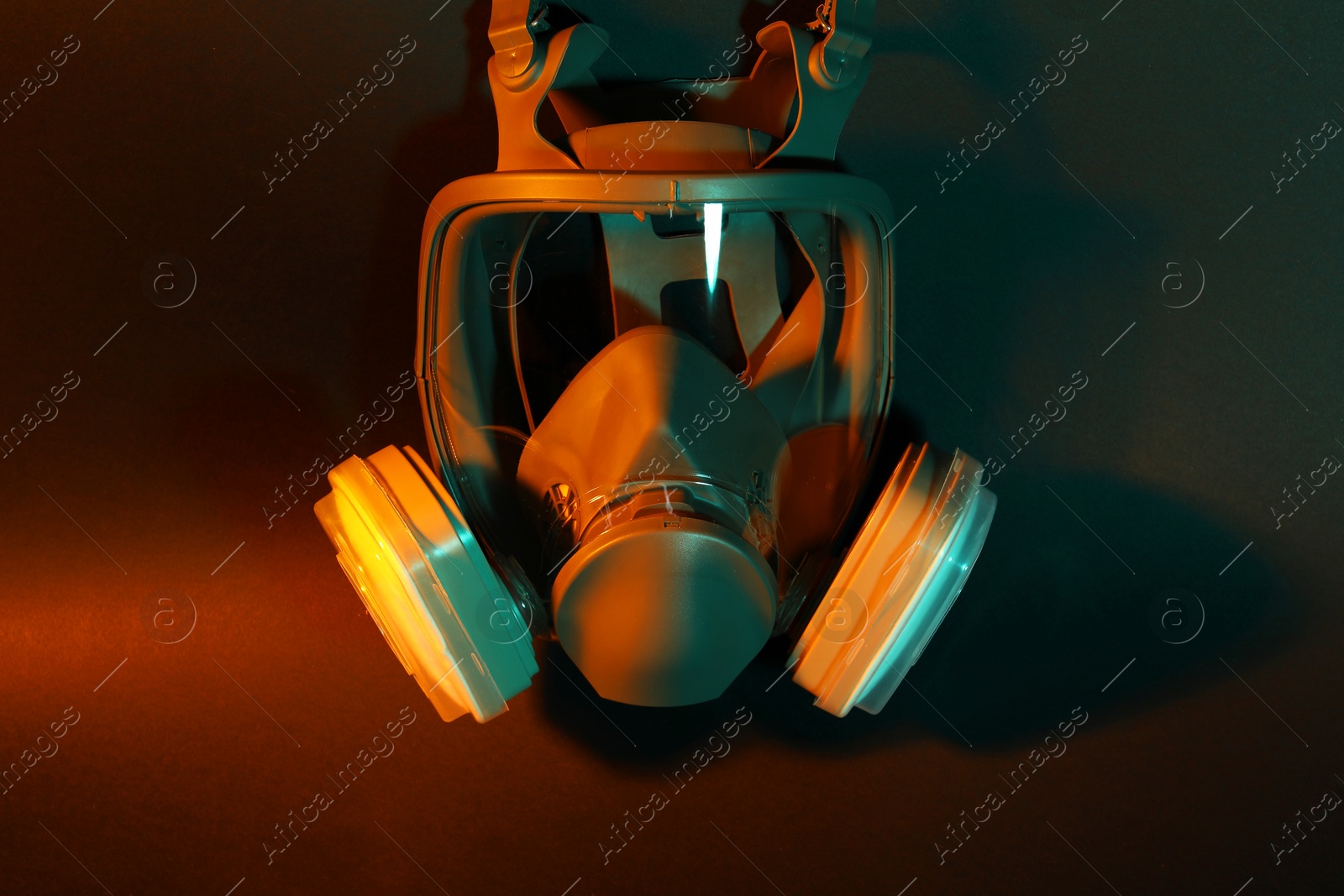 Photo of One respirator mask on dark background in orange light. Safety equipment