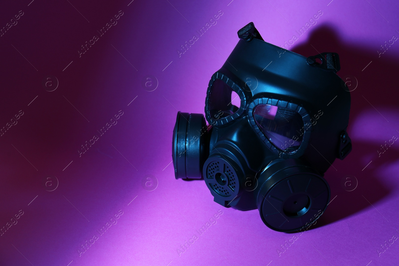 Photo of One gas mask on purple background, space for text. Safety equipment