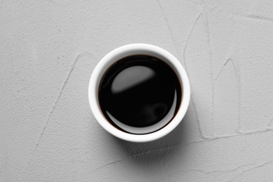 Photo of Balsamic vinegar in bowl on light grey textured table, top view