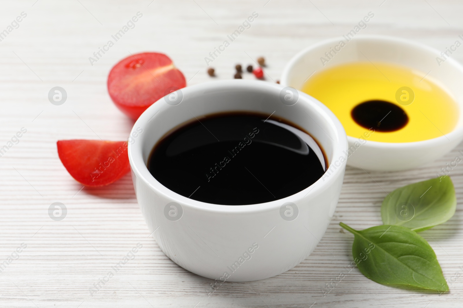 Photo of Balsamic vinegar, oil and other products on white wooden table