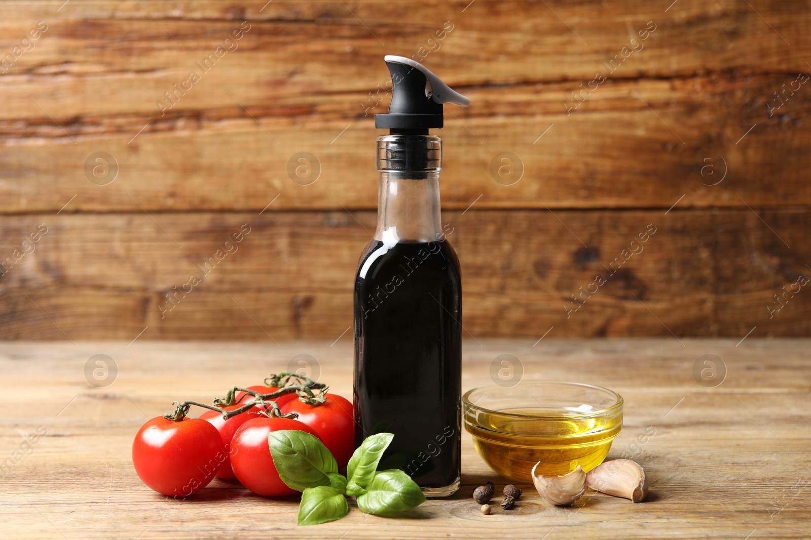 Photo of Bottle of balsamic vinegar, oil and other products on wooden table