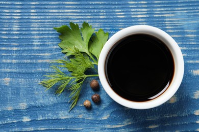 Photo of Balsamic vinegar, parsley, dill and peppercorns on blue wooden table, flat lay