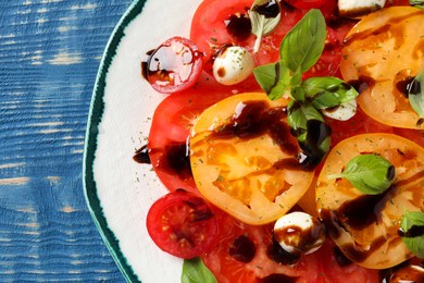 Photo of Tasty salad with balsamic vinegar and mozzarella on blue wooden table, top view