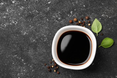 Balsamic vinegar, basil and peppercorns on black textured table, flat lay. Space for text