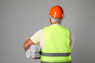 Photo of Engineer in hard hat with drafts on grey background, back view