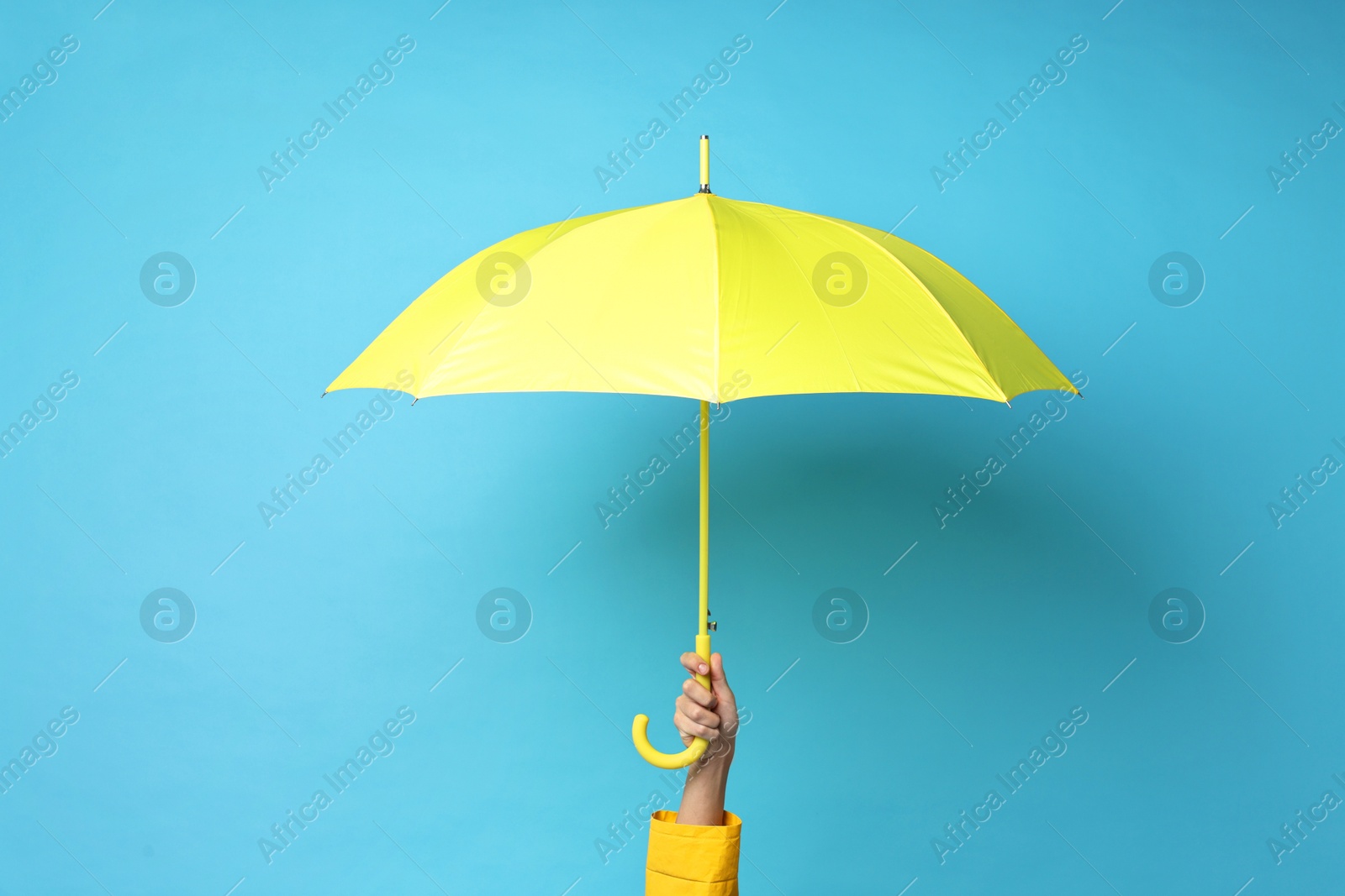 Photo of Man holding yellow umbrella on light blue background