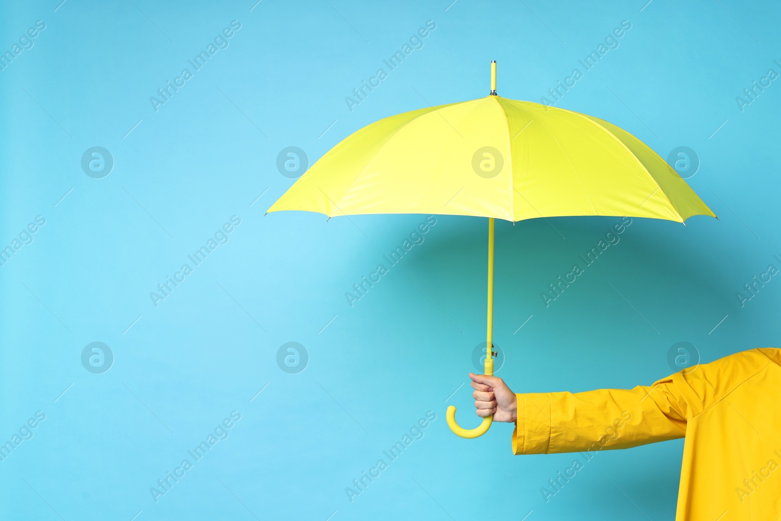 Photo of Man holding yellow umbrella on light blue background, space for text