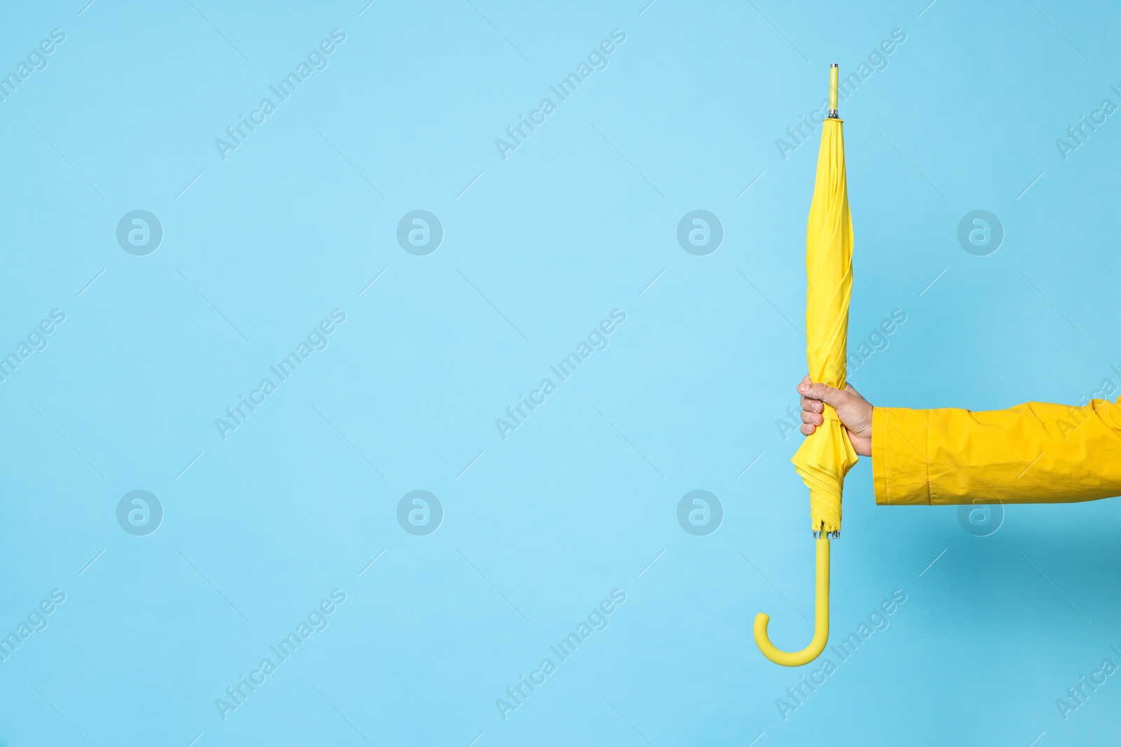 Photo of Man holding yellow umbrella on light blue background, space for text