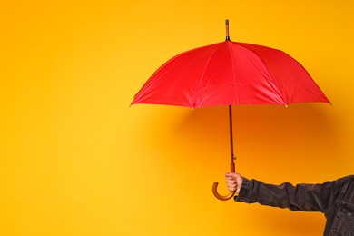 Photo of Man holding red umbrella on yellow background, closeup. Space for text