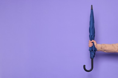 Photo of Man holding blue umbrella on purple background, closeup. Space for text