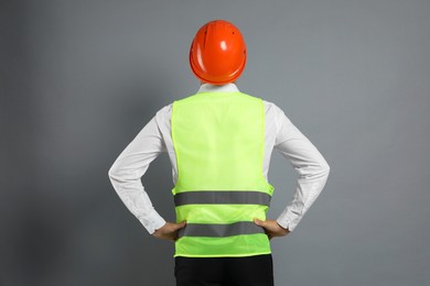 Engineer in hard hat on grey background, back view