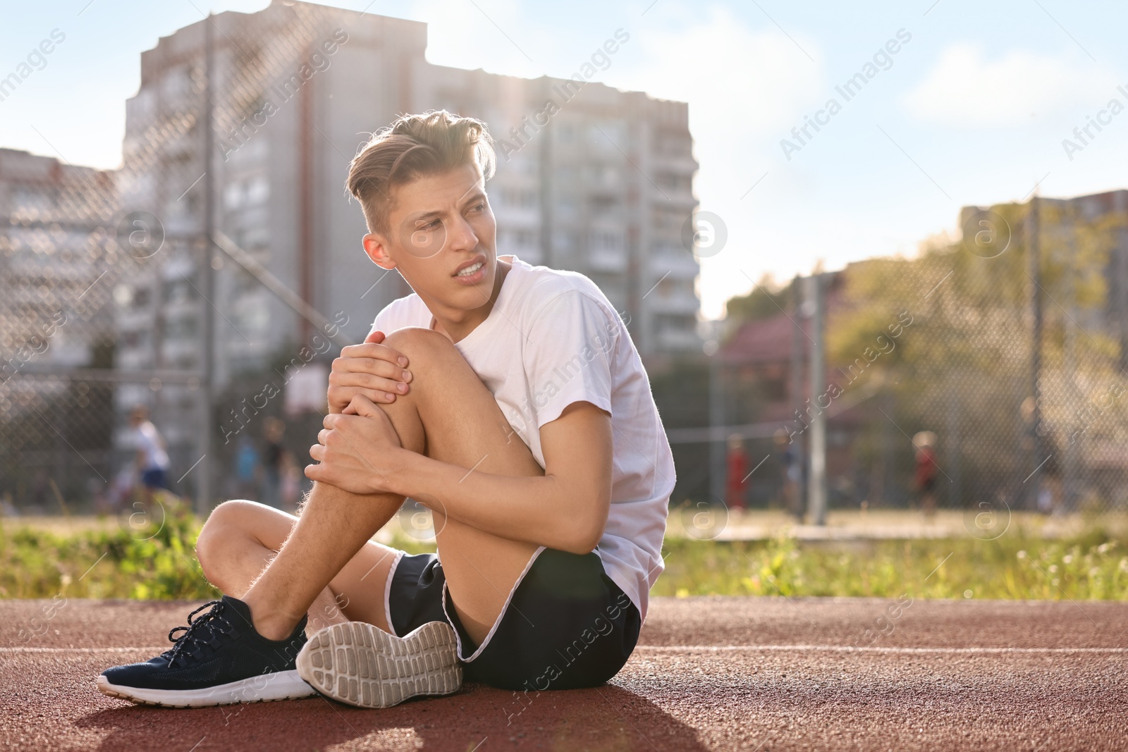 Photo of Sportsman with leg injury suffering from knee pain at stadium, space for text