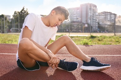 Sports injury. Man suffering from leg pain at stadium