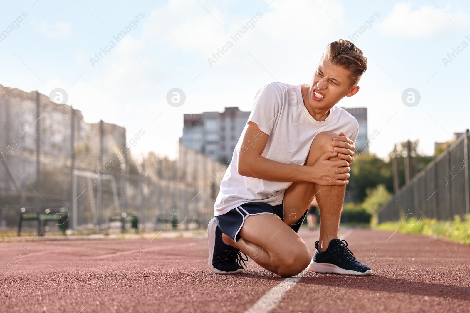 Photo of Sportsman with leg injury suffering from knee pain at stadium, space for text