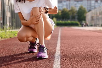 Sportswoman with leg injury suffering from knee pain at stadium, closeup. Space for text