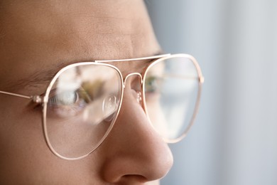 Vision correction. Man wearing glasses on blurred background, closeup