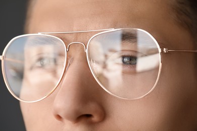 Vision correction. Man wearing glasses on grey background, closeup