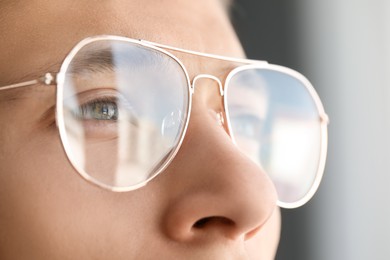 Photo of Vision correction. Man wearing glasses on blurred background, closeup