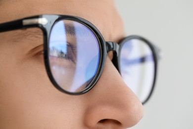 Vision correction. Man wearing glasses on blurred background, closeup