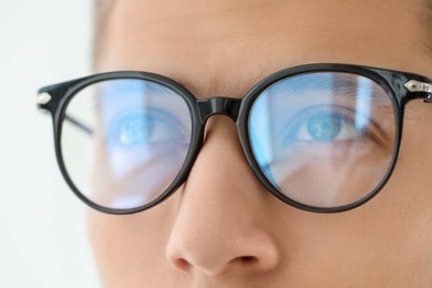 Photo of Vision correction. Man wearing glasses on blurred background, closeup