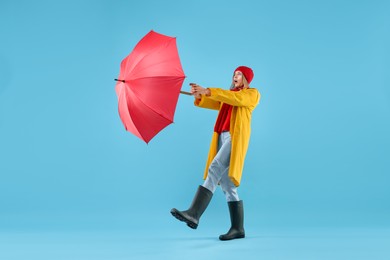 Woman with red umbrella on light blue background