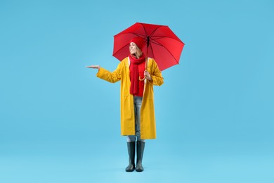 Photo of Woman with red umbrella on light blue background