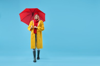 Woman with red umbrella on light blue background