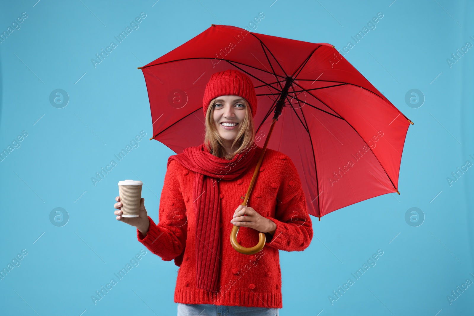 Photo of Woman with red umbrella and paper cup on light blue background