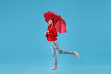 Photo of Woman with red umbrella on light blue background