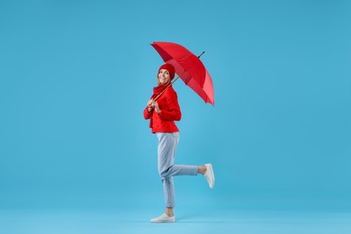 Woman with red umbrella on light blue background