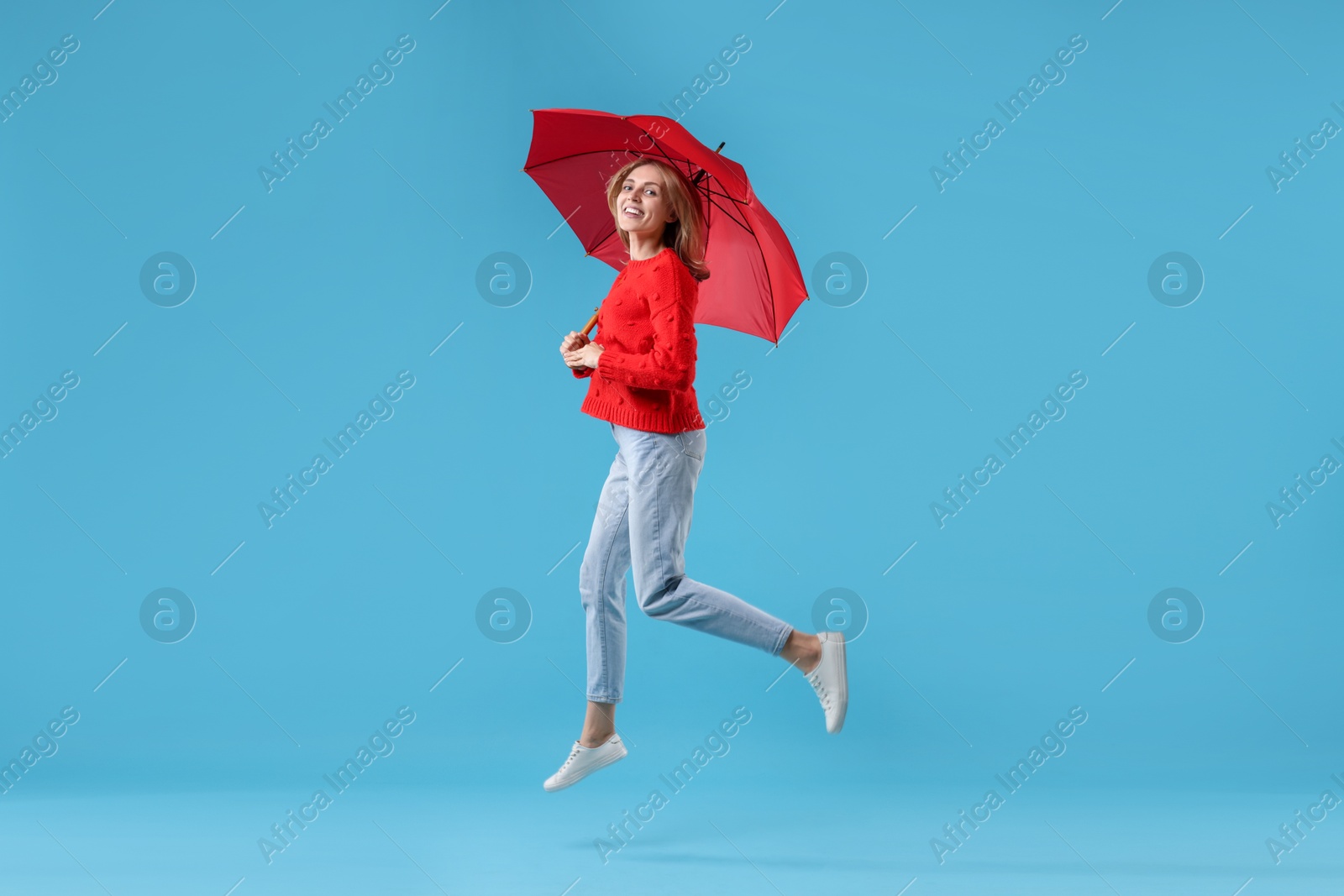 Photo of Woman with red umbrella on light blue background