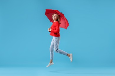 Woman with red umbrella on light blue background