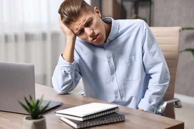 Young man suffering from sinusitis at wooden table indoors