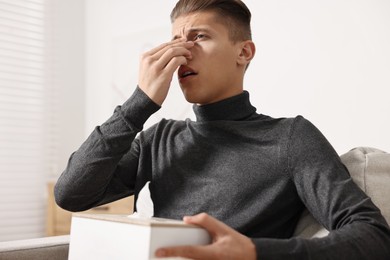 Young man with tissues suffering from sinusitis at home