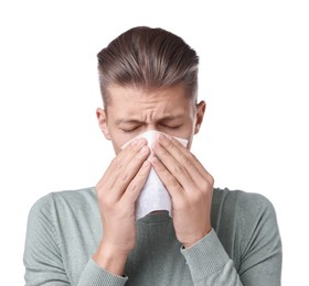 Young man with tissue suffering from sinusitis on white background